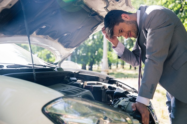 man looking under the hood of a car