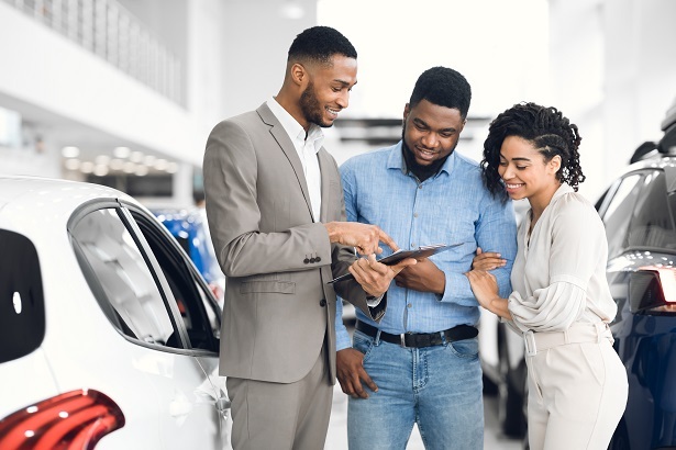 couple looking at the dealer sticker price of a new car